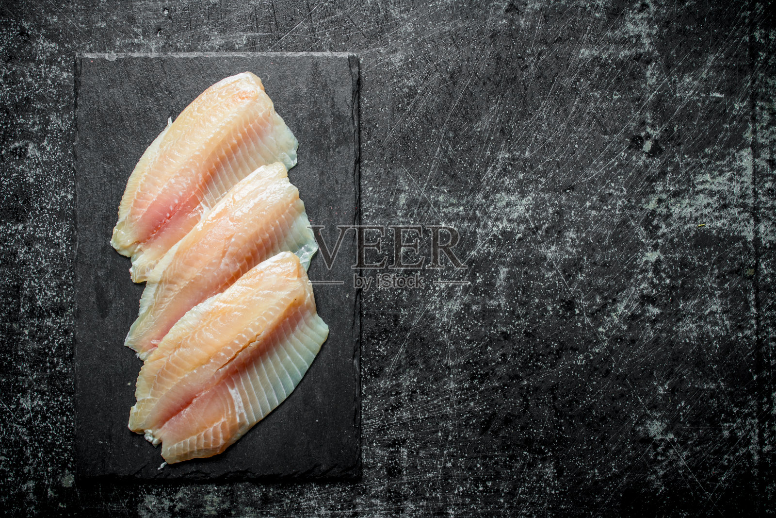 鱼片放在一块黑色的石板上。照片摄影图片