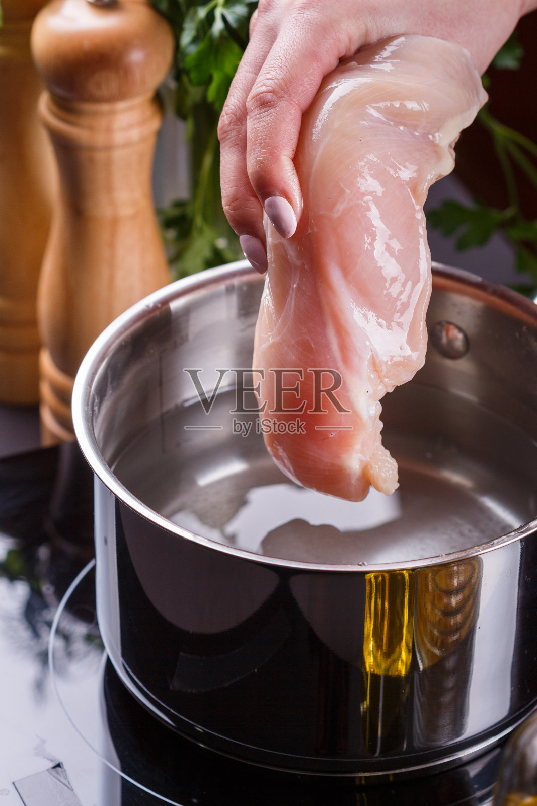 穿着灰色围裙的年轻女子煮鸡胸肉照片摄影图片