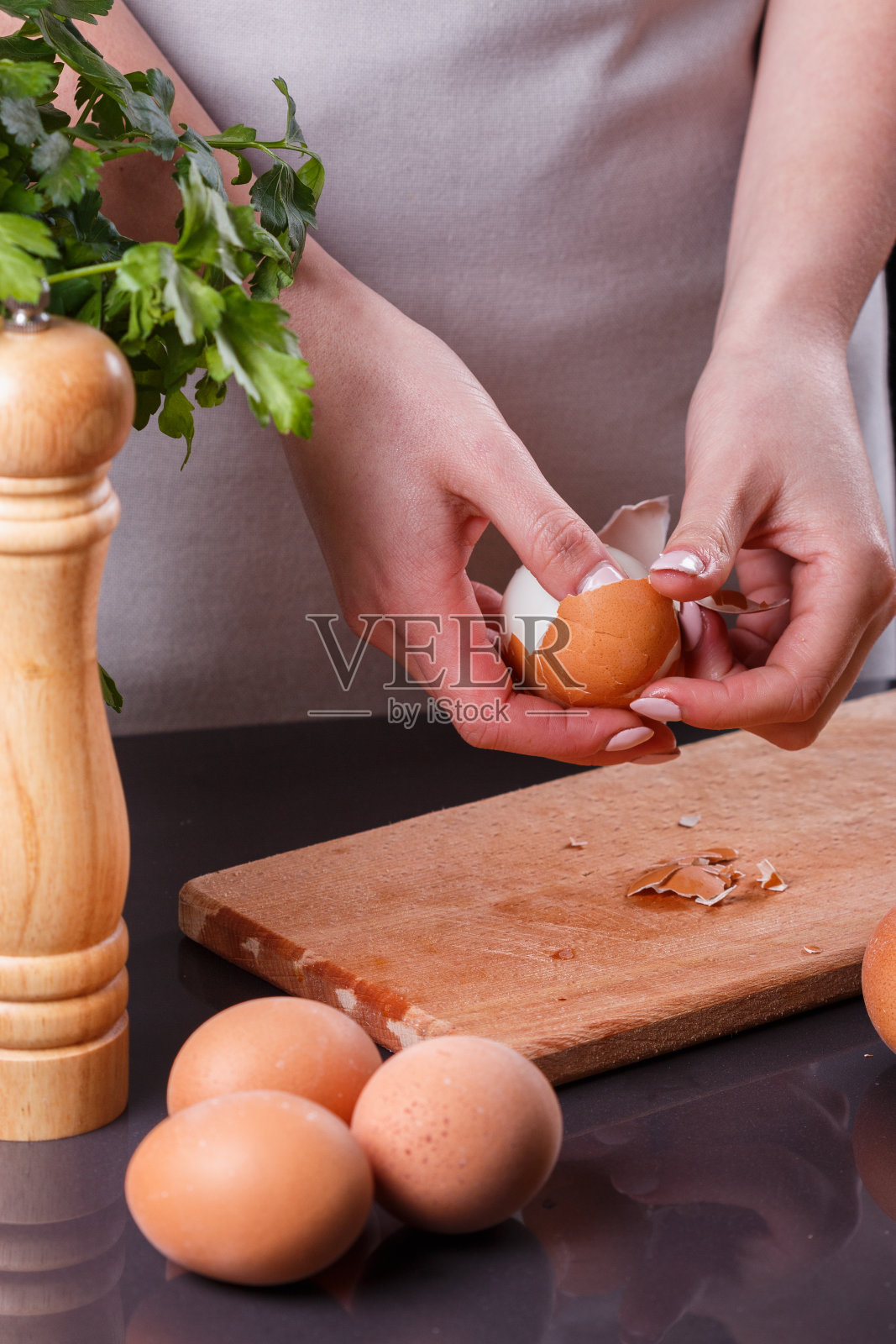 穿着灰色围裙的年轻女子在清洗煮鸡蛋照片摄影图片