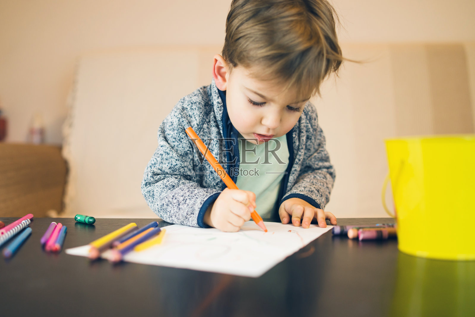 2岁小男孩的肖像，用蜡笔在白纸上写字，画画，在家里的桌子旁玩耍。照片摄影图片