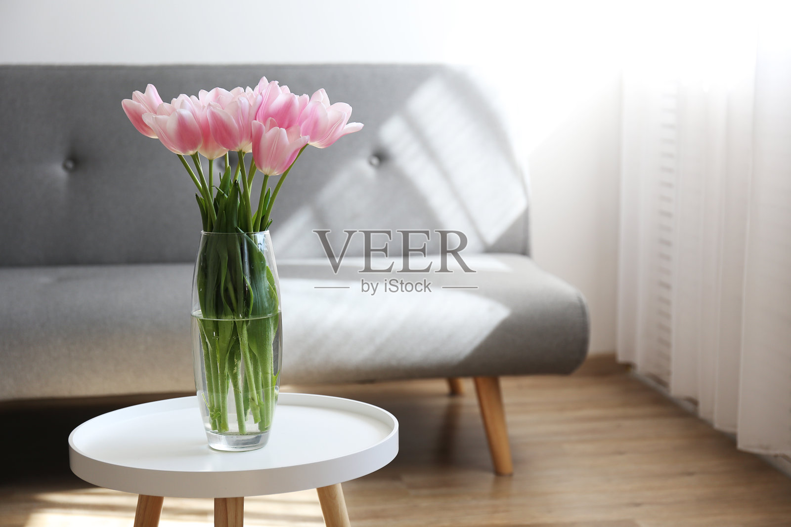 室内高大，玻璃花瓶桌上放着鲜花。照片摄影图片