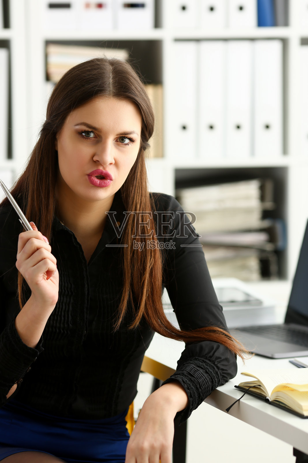 美丽微笑的女孩在工作场所拿着银笔照片摄影图片