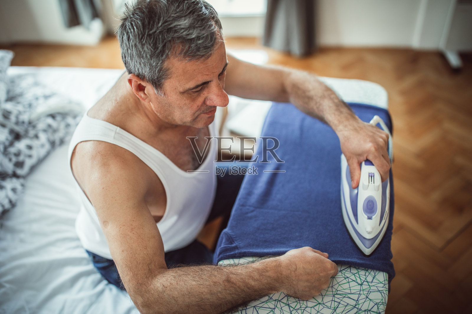 一个男人在卧室熨衣服照片摄影图片