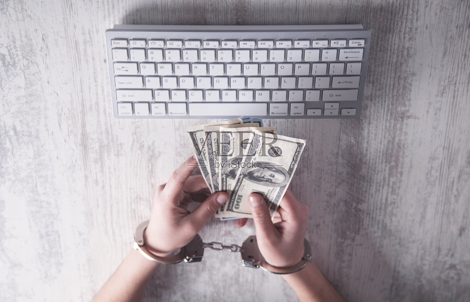 手被铐在钱的手铐里。网络犯罪的概念照片摄影图片