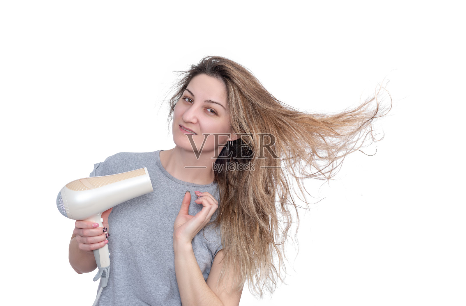 拿着电吹风的年轻女子，被孤立在白色背景中。照片摄影图片