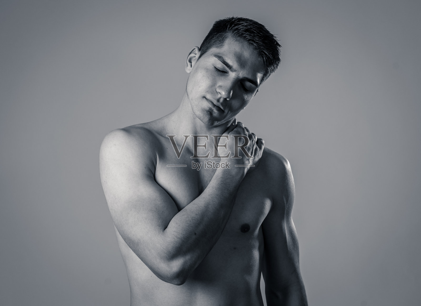 年轻的肌肉健康的人触摸和抓颈部和上背部后遭受颈部疼痛。在中性背景下隔离。在运动损伤中不正确的姿势问题和身体保健。照片摄影图片