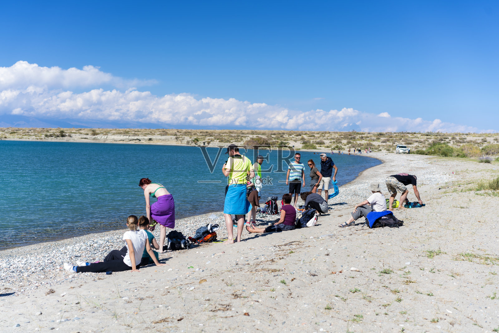 游客在伊塞克库尔湖游泳后穿衣，吉尔吉斯斯坦照片摄影图片