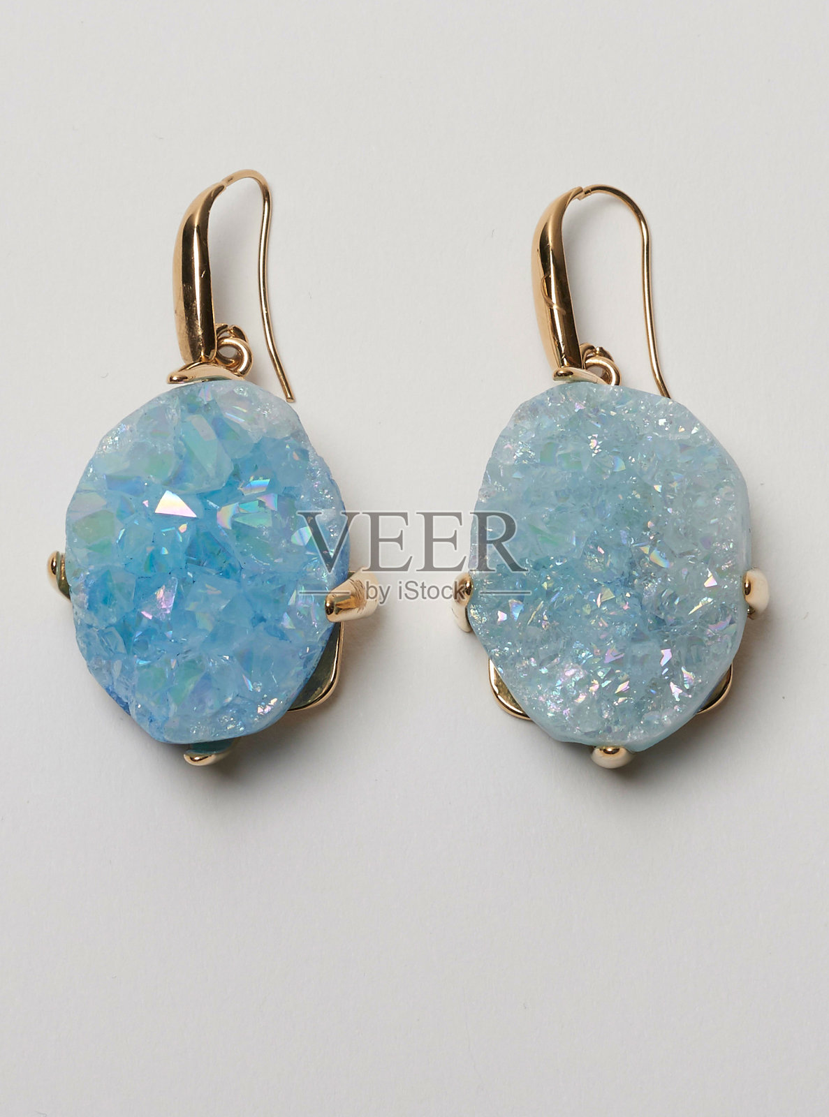 金色环耳环与美丽的蓝色石头钉与白色的背景照片摄影图片