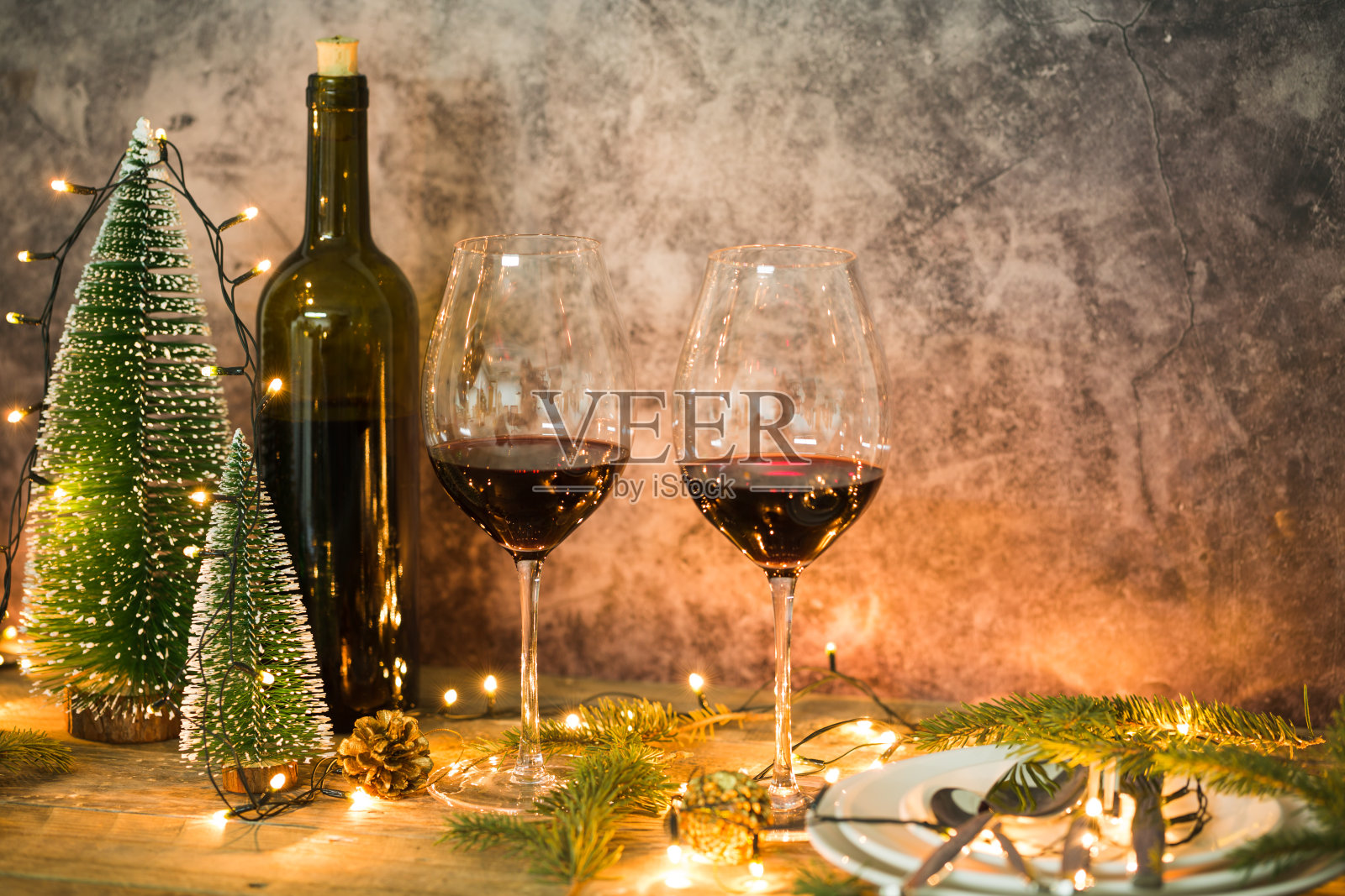 挂着圣诞彩灯的红酒杯照片摄影图片