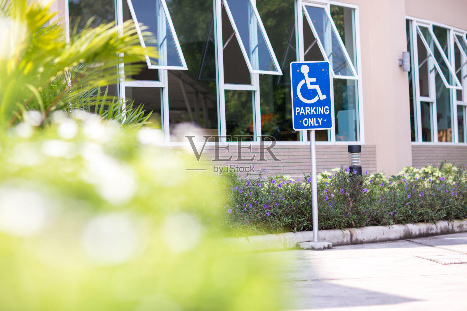 在零售停车场为预留购物者预留的停车位。残疾人或轮椅停车位。在停车场有一个标志标明为残疾人预留停车位。照片摄影图片