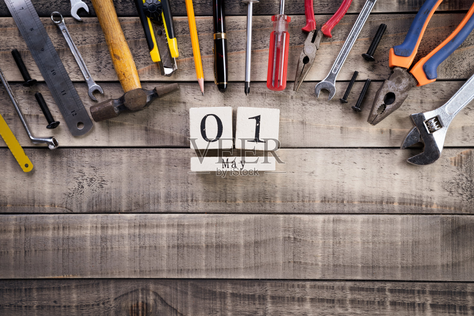 劳动节，木块日历与许多方便的工具上木制的背景纹理。照片摄影图片