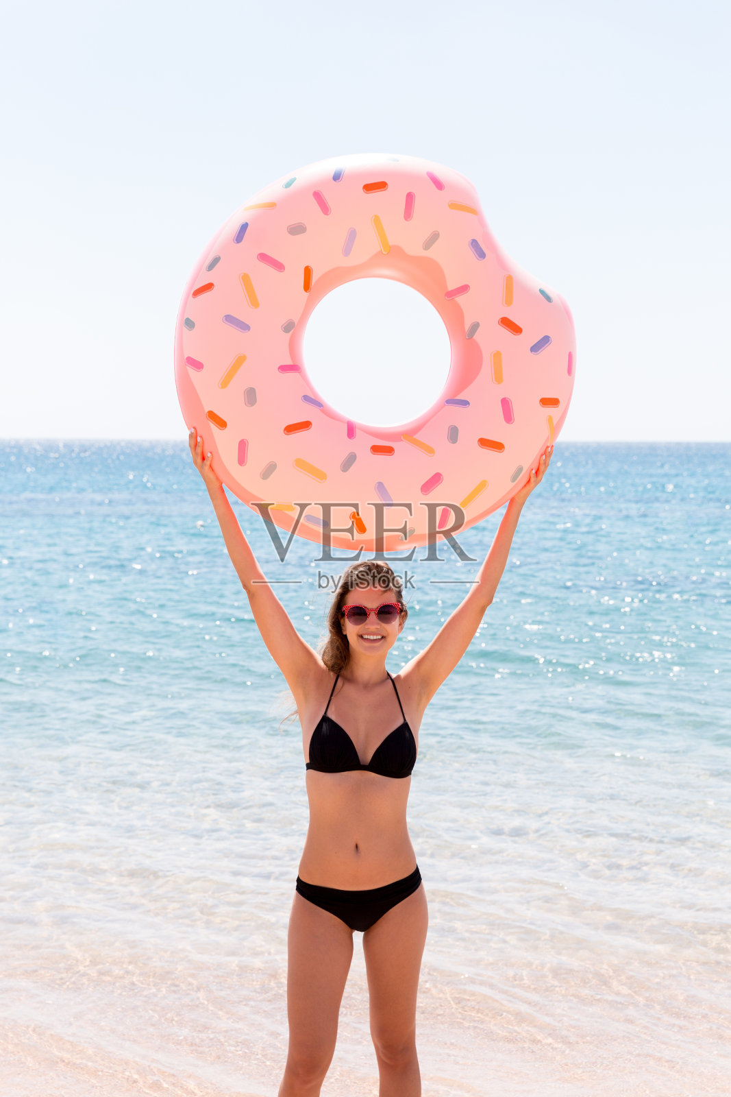 快乐的女人在海滩上玩甜甜圈游泳圈，夏季假期概念照片摄影图片