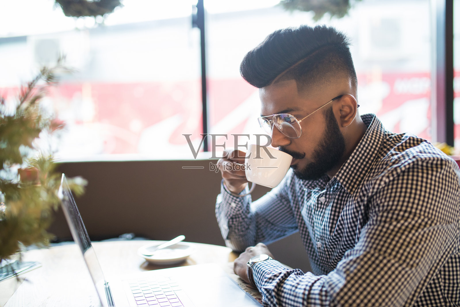 微笑的年轻印度人在咖啡馆里使用笔记本电脑照片摄影图片