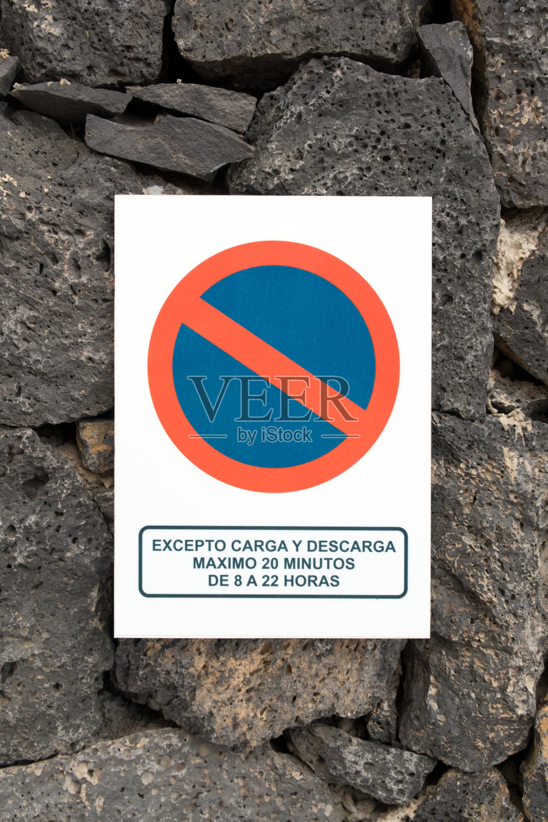 禁止在石头上张贴有西班牙语信息的停车标志照片摄影图片