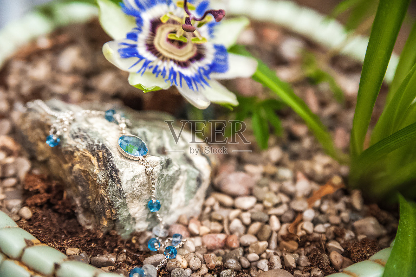 以盛开的帕西花为背景，用天然宝石制成的首饰。手镯，戒指，项链，手工耳环特写。天然石材和珠宝的纹理照片摄影图片