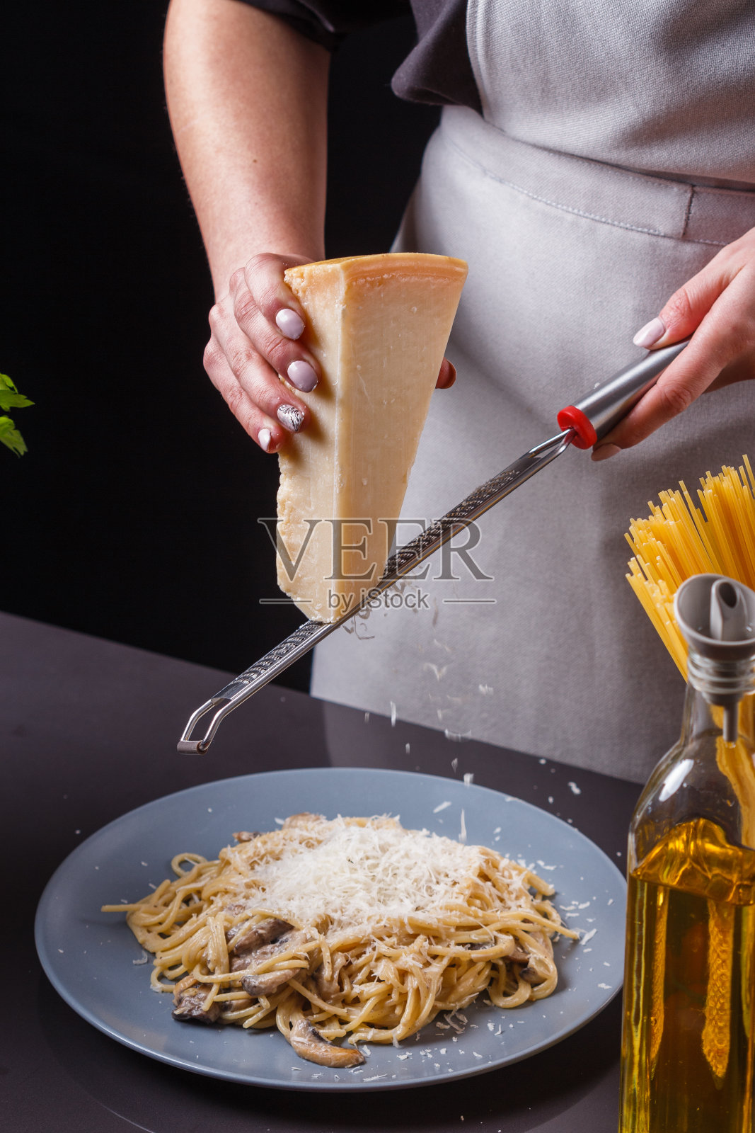 穿着灰色围裙的年轻女子在做意大利面照片摄影图片
