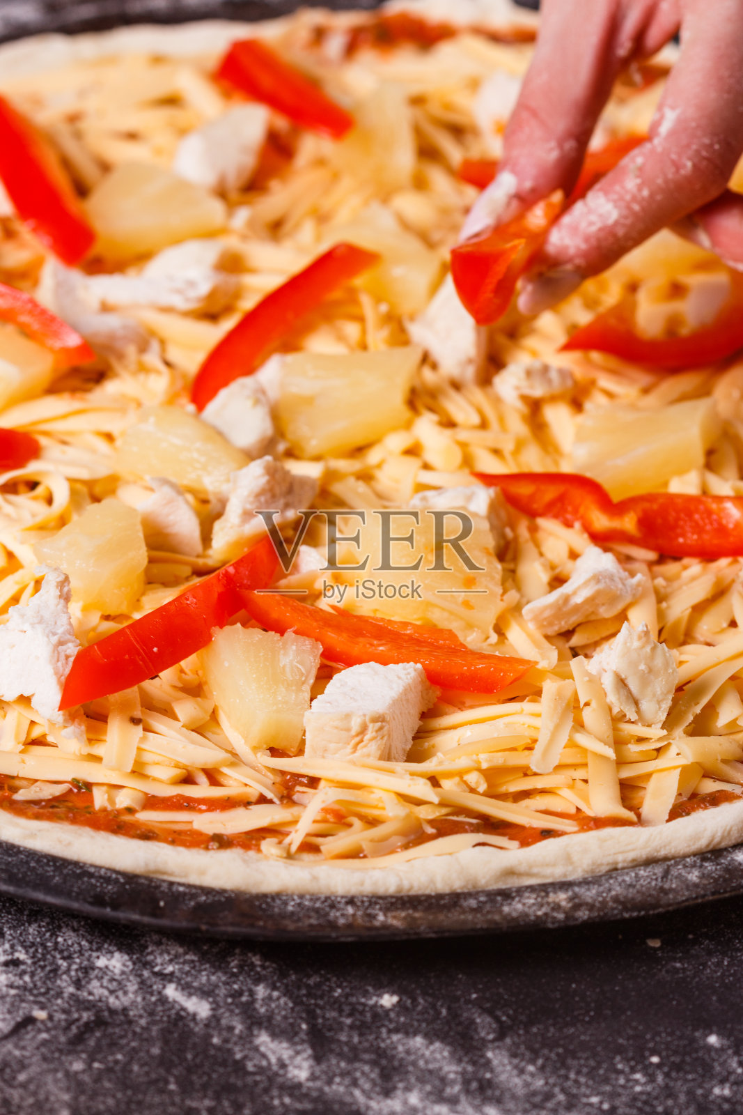 身穿灰色围裙的年轻女子正在做夏威夷披萨照片摄影图片