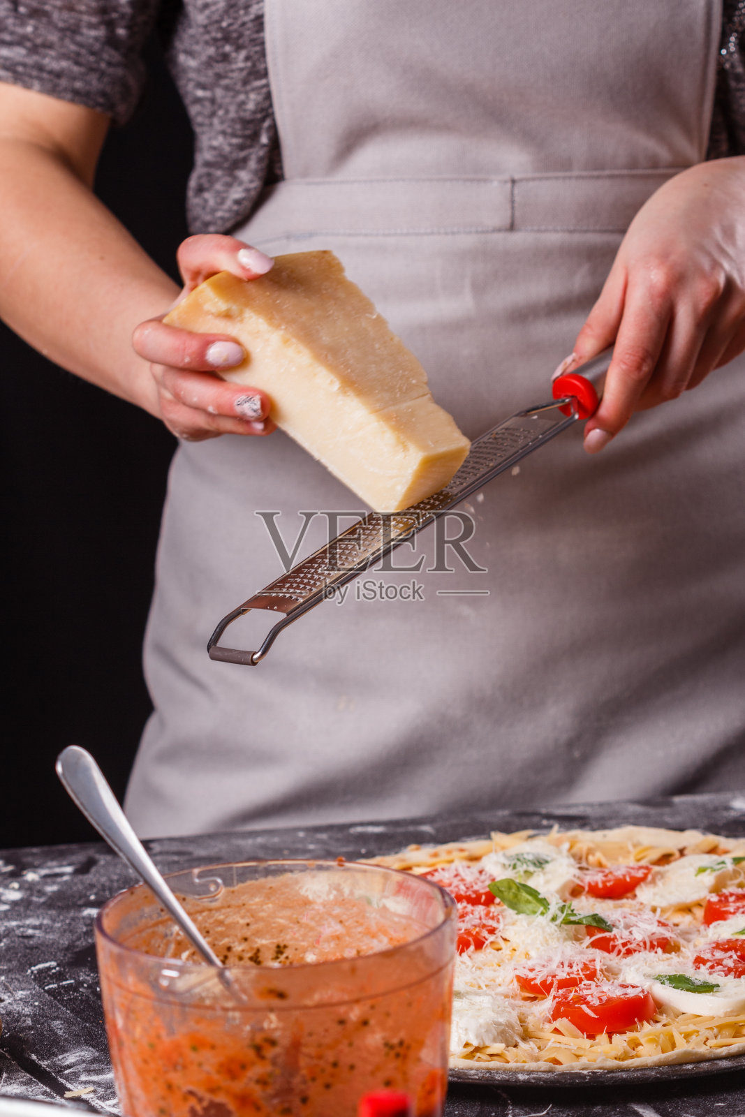 穿着灰色围裙的年轻女子准备了一杯玛格丽塔披萨照片摄影图片