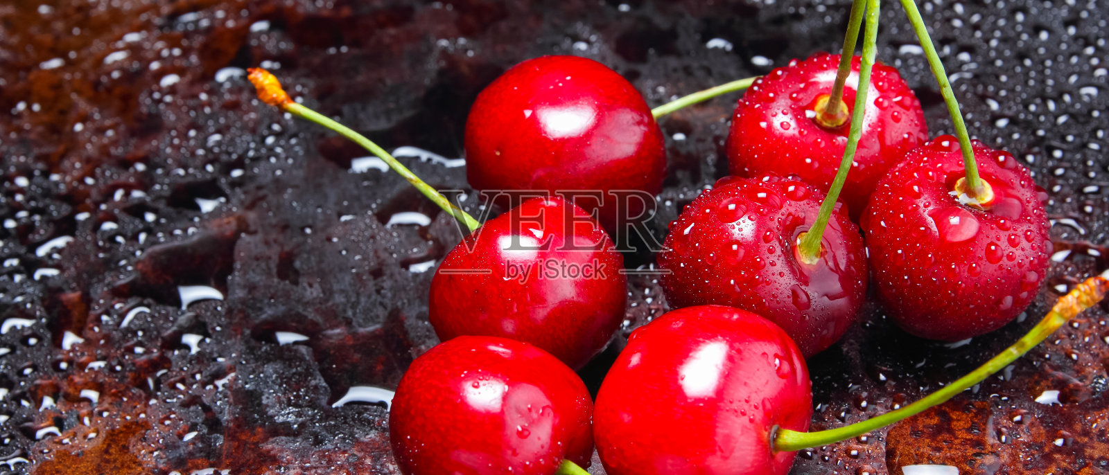 水滴里的红樱桃。深色背景上的新鲜樱桃。素食的浆果。煮樱桃前洗净照片摄影图片