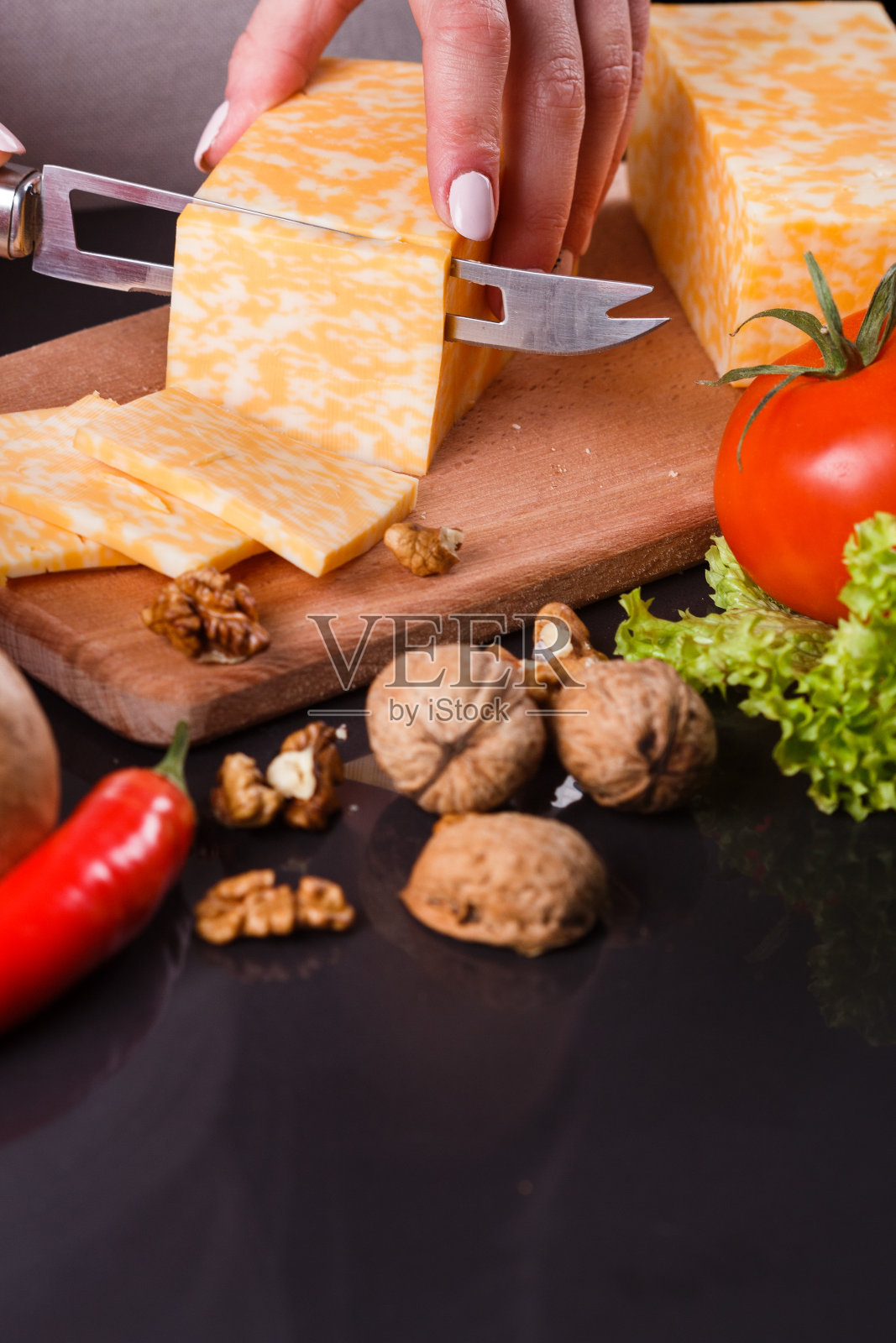 穿着灰色围裙切奶酪的年轻女子照片摄影图片