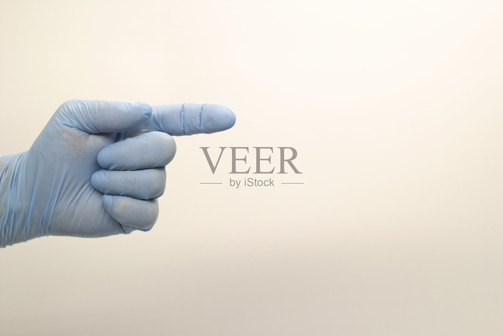 外科医生的手戴着蓝色医用手套，在一个孤立的背景上显示一个标志。照片摄影图片