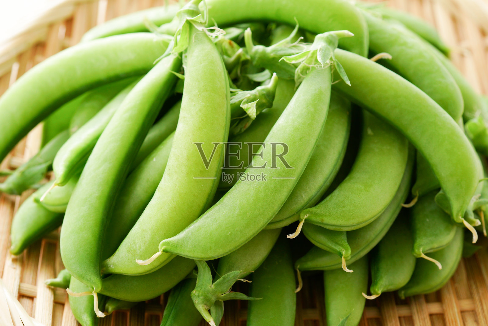 用竹滤锅把花园里的豌豆拍碎。照片摄影图片