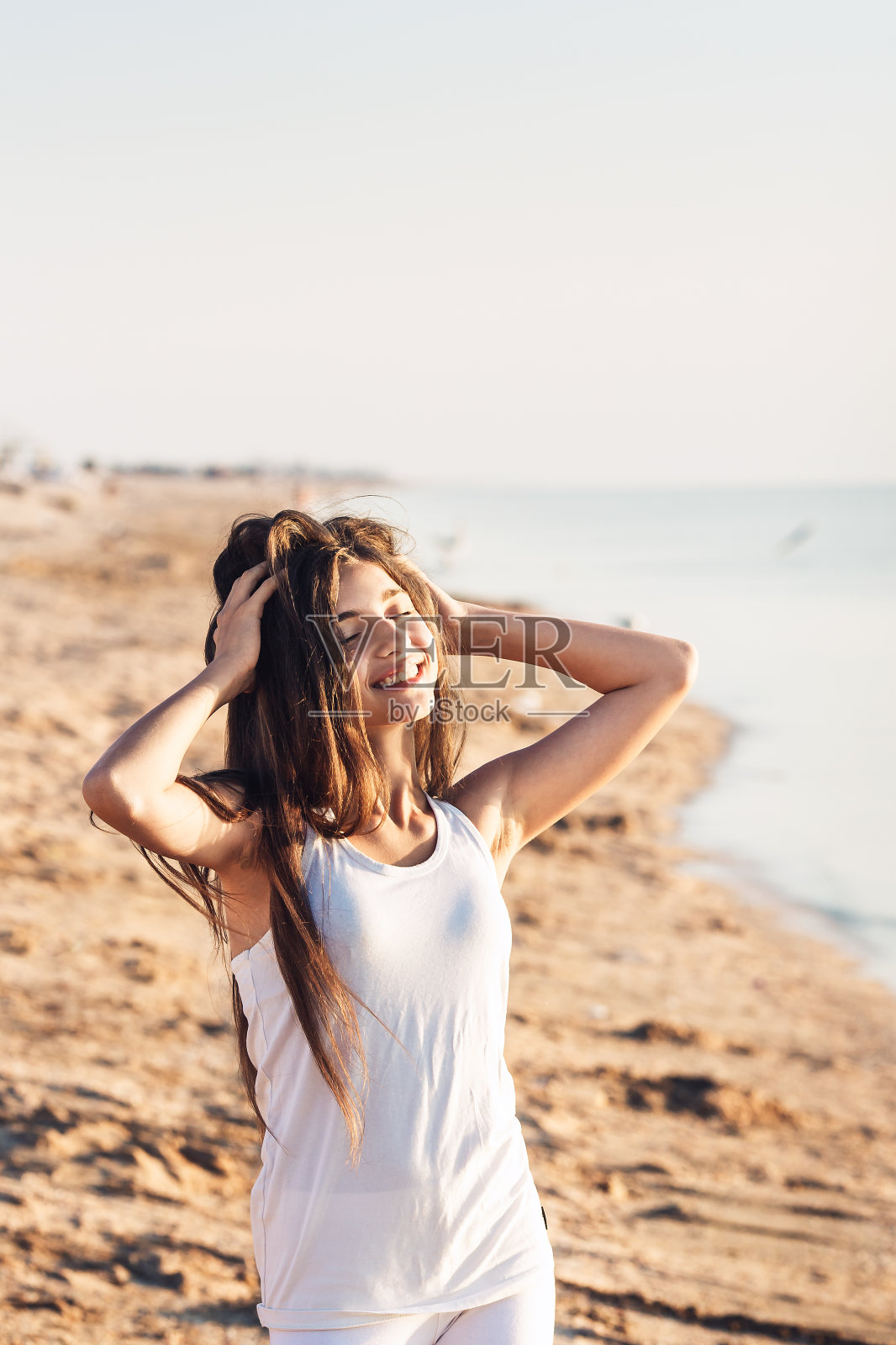 可爱的小女孩在沙滩上休息，享受着温暖的阳光。照片摄影图片