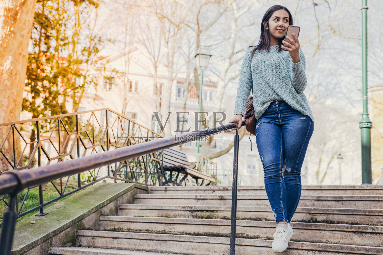 一名手持智能手机走下城市楼梯的年轻女子照片摄影图片