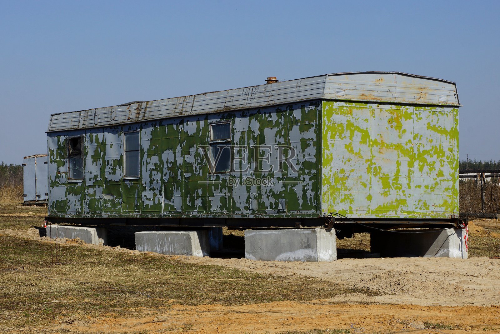 灰绿色的带窗户的旧金属容器伫立在田野的干草中照片摄影图片