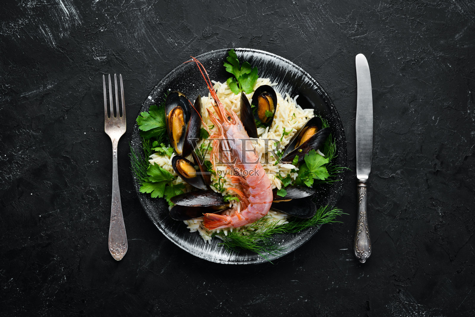 米饭和海鲜。虾仁贻贝烩饭。在一个黑色的盘子里。前视图。免费空间。照片摄影图片