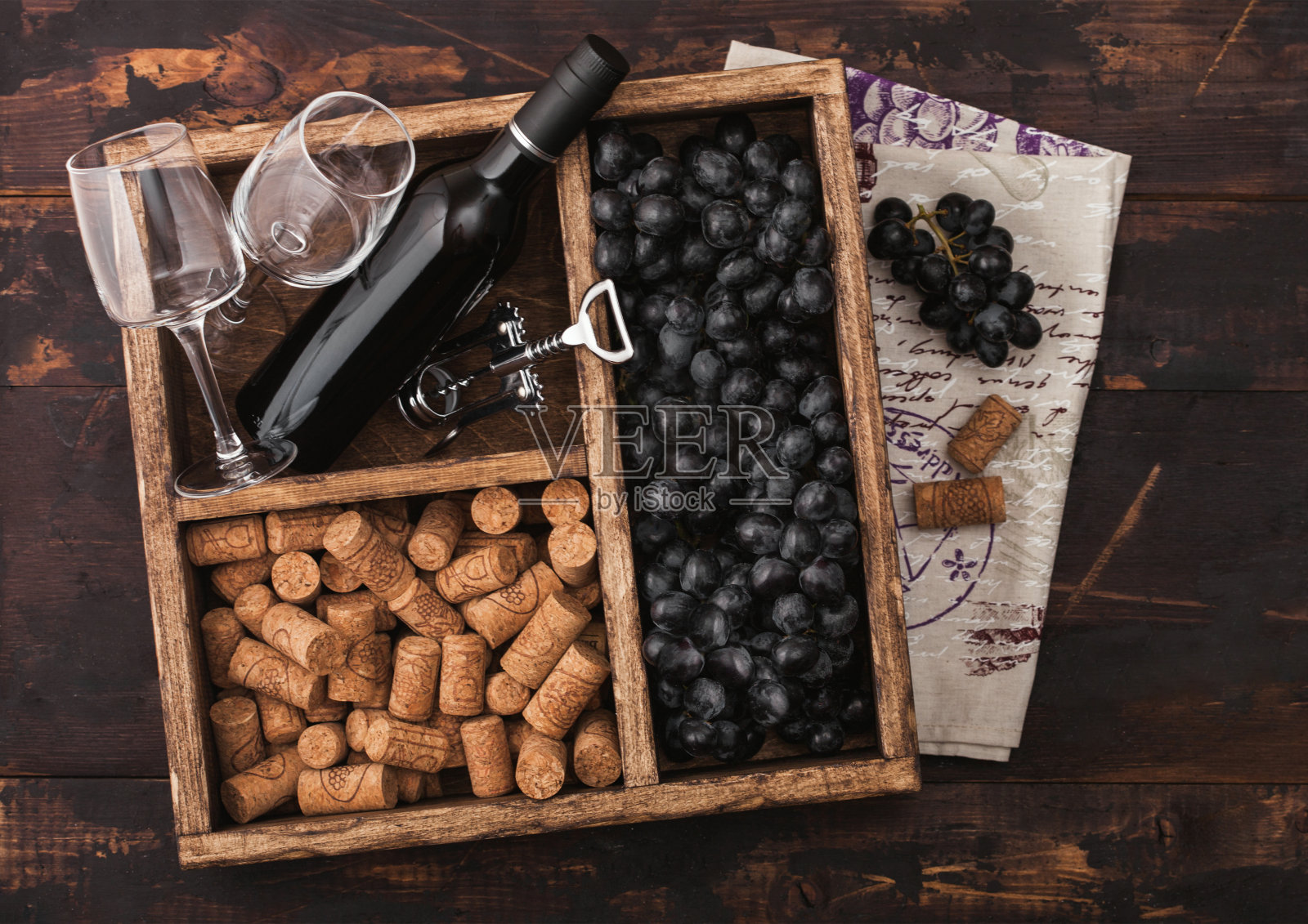 豪华的红酒和空酒杯与黑葡萄与软木塞和螺旋塞在古董木箱上的深色木制背景和亚麻毛巾。俯视图照片摄影图片