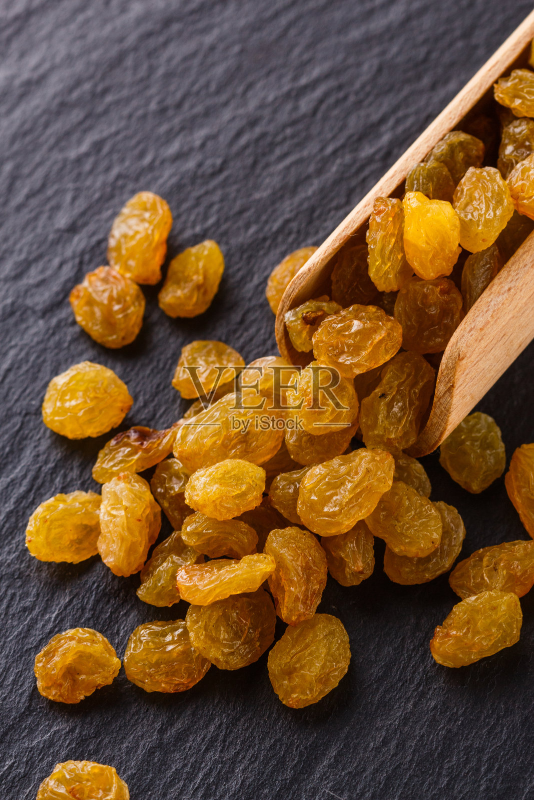 深色石头背景上的金色葡萄干照片摄影图片