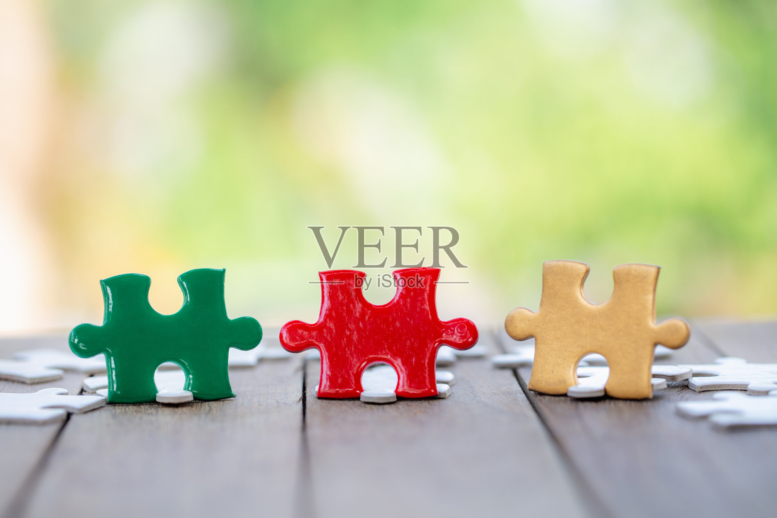 一块红、绿、金的拼图在旧木头上。团队合作理念照片摄影图片