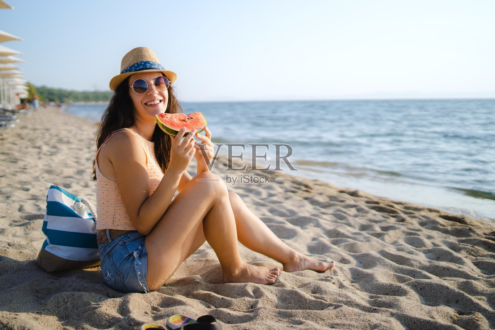 年轻女子在沙滩上拿着西瓜照片摄影图片