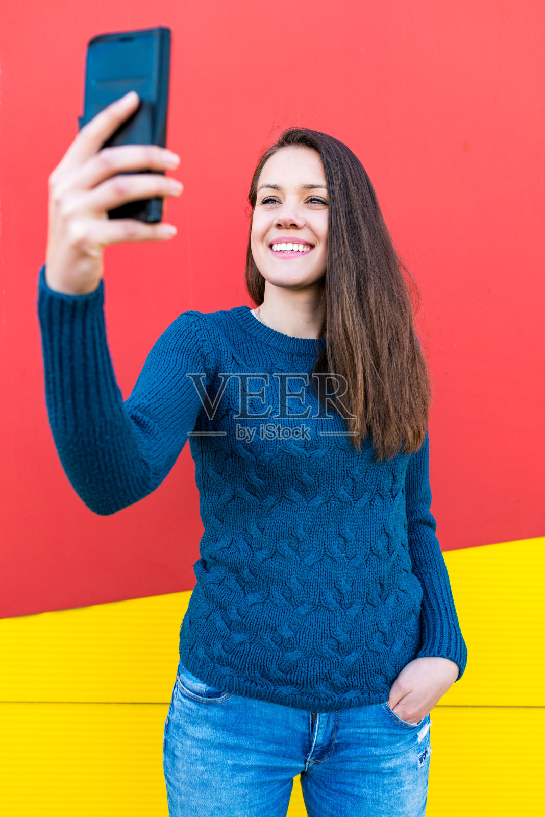 美丽的年轻女子与智能手机的自拍鲜明多彩的背景照片摄影图片