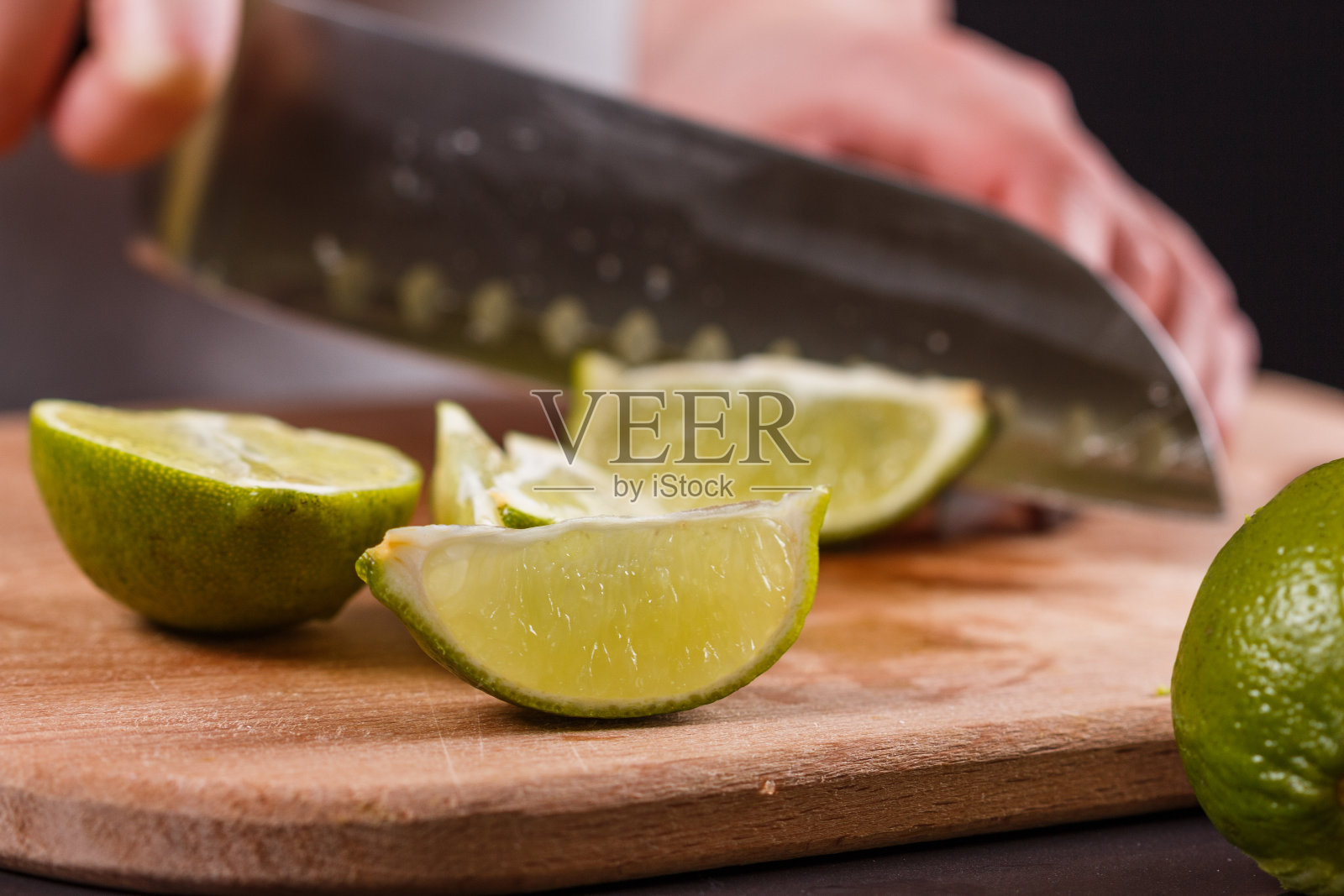 穿着灰色围裙的年轻女子剪着青柠皮照片摄影图片
