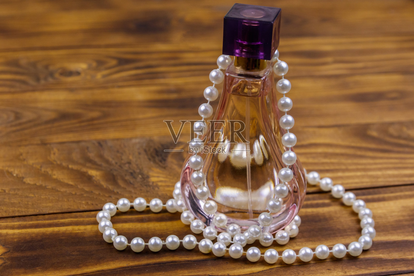 香水瓶和珍珠项链的木制背景照片摄影图片