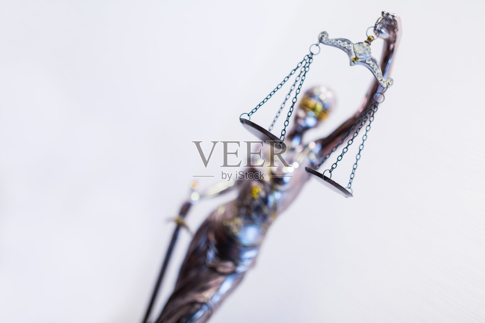 正义小雕像-忒弥斯，古希腊的神圣法律和正义女神，被描述为智慧和好建议的女士，戴着眼罩，手持剑，举起公正的天平照片摄影图片