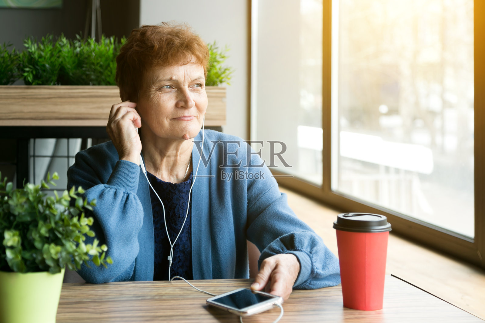一位上了年纪的妇女戴着耳机听音乐。照片摄影图片