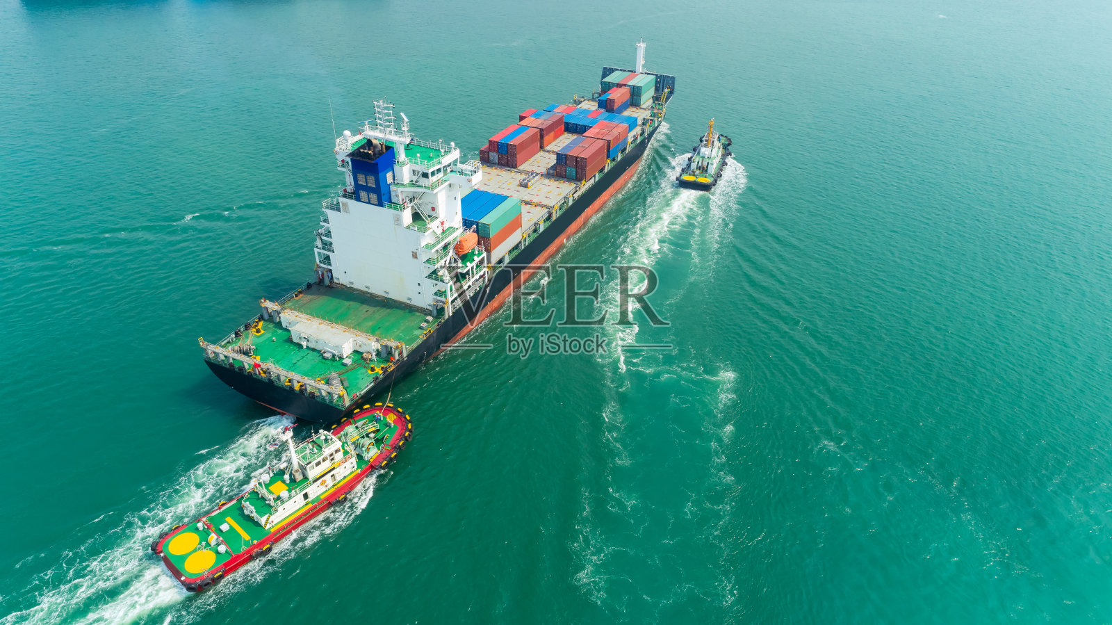 鸟瞰图拖船拖集装箱船到海港物流，进出口，航运或运输。照片摄影图片