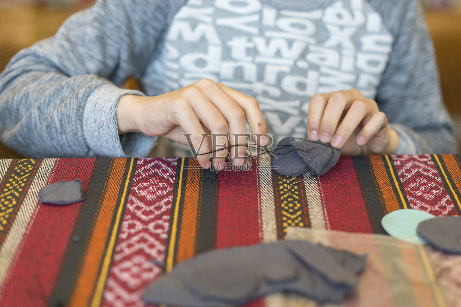 拿着针线的小女孩。创造。小女孩缝制毛毡玩具。照片摄影图片