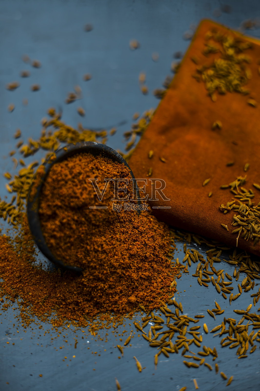 在一块布或餐巾纸上的一个粘土碗里，在木头表面上撒上小茴香粉或生小茴香粉。照片摄影图片