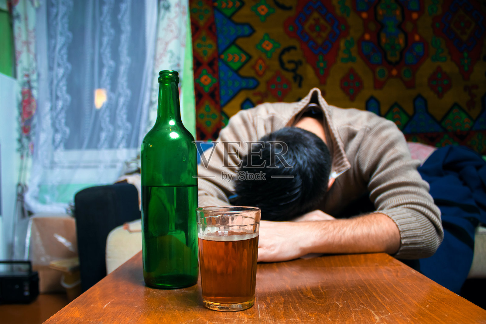 一个醉汉拿着酒杯和酒瓶坐在桌子旁照片摄影图片