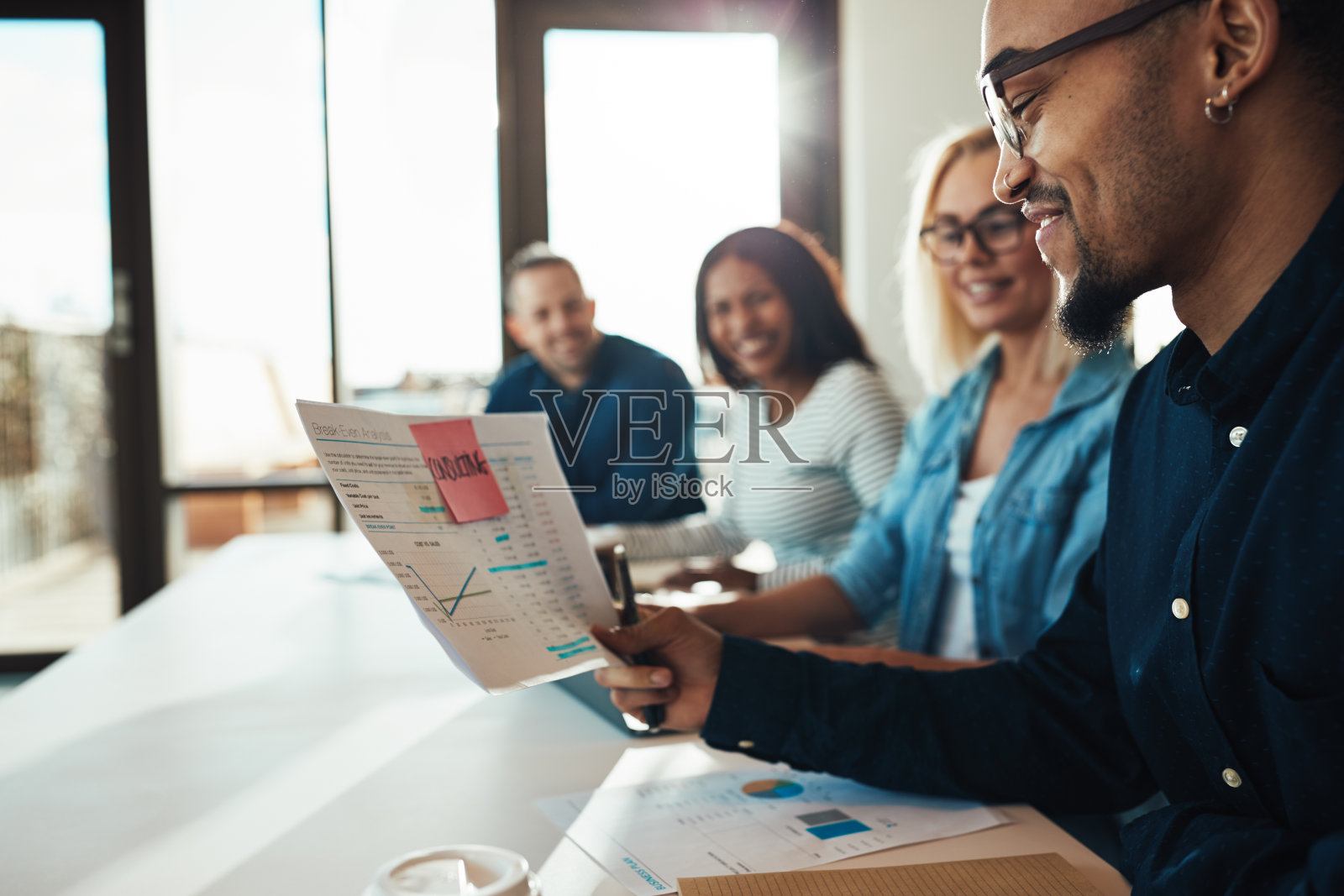 笑容可掬的年轻非洲裔美国商人正在开会时阅读文件照片摄影图片