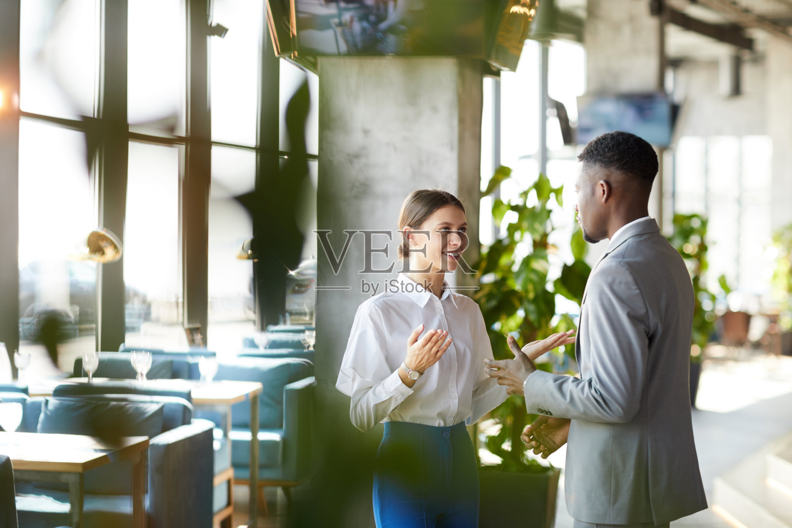 积极自信的多民族商务同事穿着正装站在现代餐厅，在讨论策略时打手势照片摄影图片