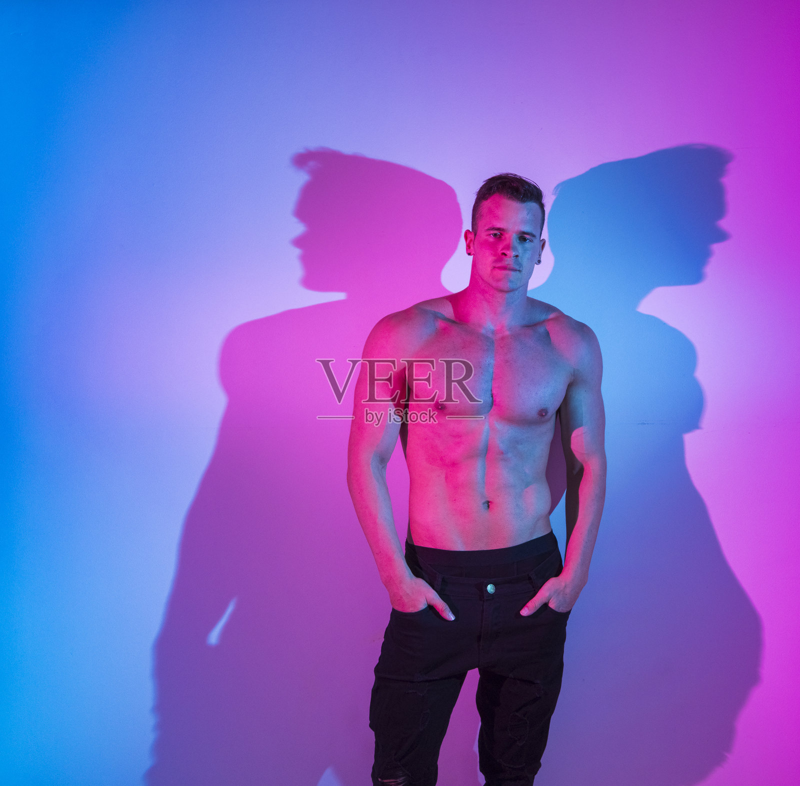 英俊的赤膊男子穿着黑色牛仔裤站在白墙前照片摄影图片