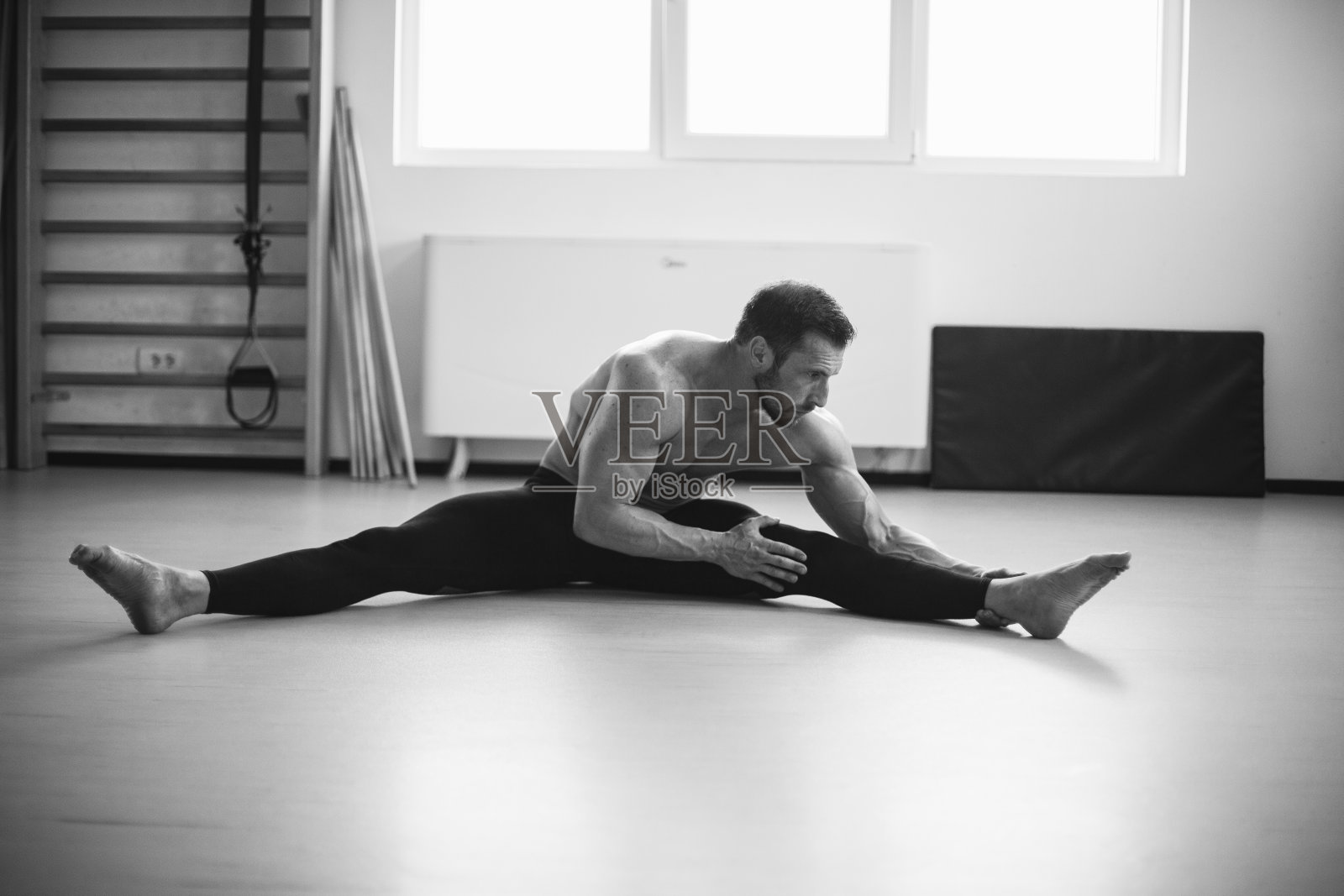 留着胡子的运动员在健身房里伸展身体照片摄影图片