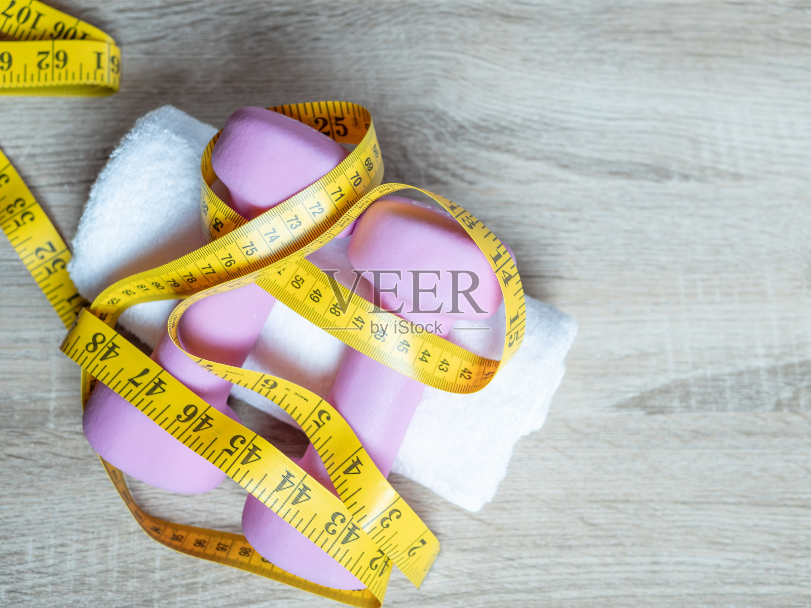 健身设备与哑铃和毛巾在木地板的背景。从上面俯瞰。健康和运动概念与复制空间照片摄影图片