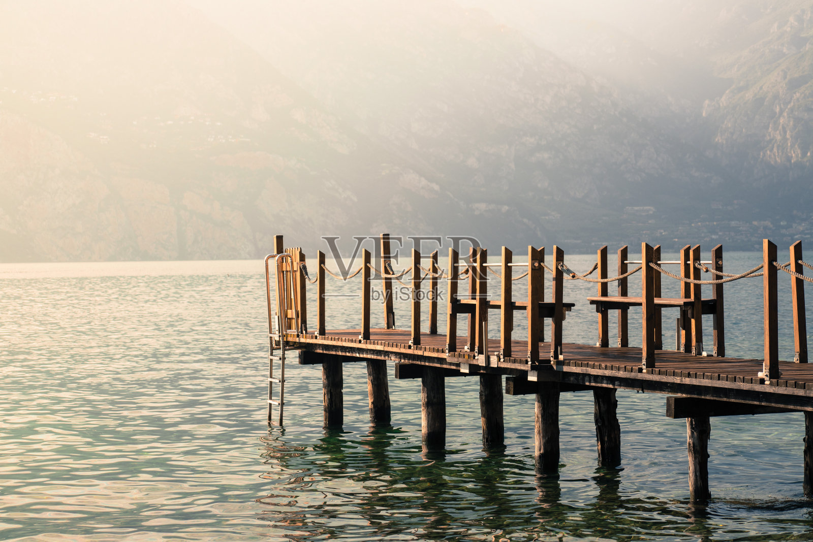 暑假:蓝色湖水上的木制码头。多云的夜晚风景。照片摄影图片