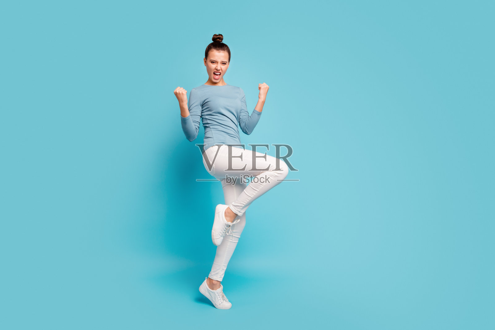 全身长度身体尺寸视图照片粗心的无忧无虑的顽皮的满意的女士尖叫耶举起手拳头幸运的幸运彩票的目的有趣的时髦的套头衫白色裤子运动鞋孤立的蓝色背景照片摄影图片
